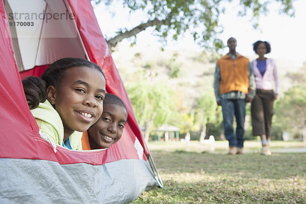 Children peeking out of tent at campsite