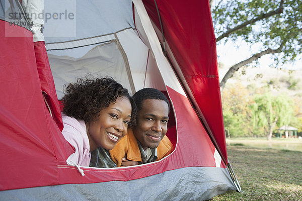 Couple peeking out of tent at campsite