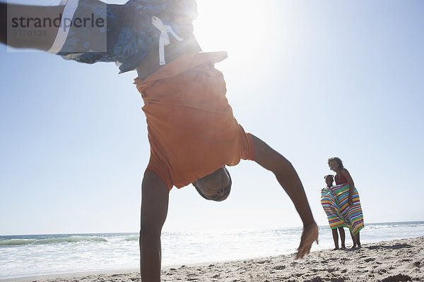 Boy doing cartwheel on beach