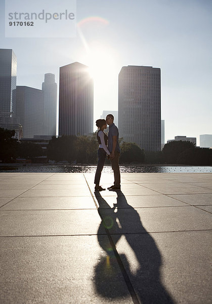 Couple casting shadows on urban waterfront