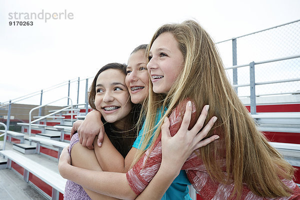 Teenage girls hugging on bleachers