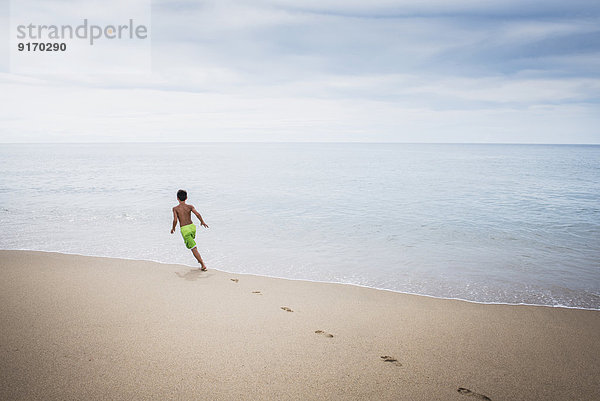 Mixed race boy playing on beach