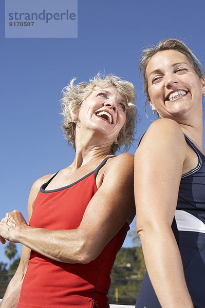 Women laughing back to back outdoors