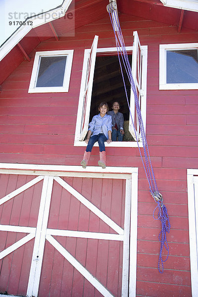 Mixed race children looking out barn window