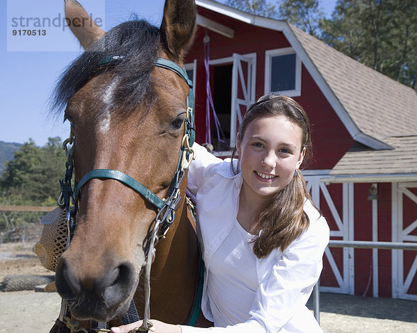 Mixed race girl smiling with horse on ranch