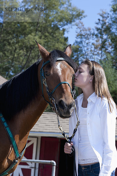 Mixed race girl kissing horse on ranch