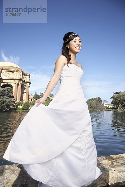 Chinese bride smiling in urban park  San Francisco  California  United States