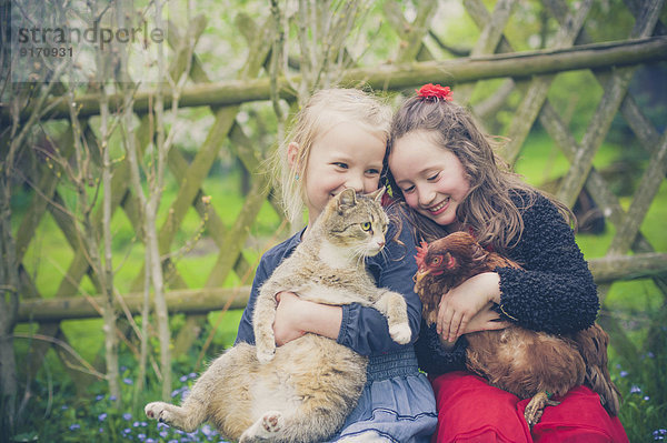 Portrait von zwei kleinen Mädchen mit Katze und Huhn