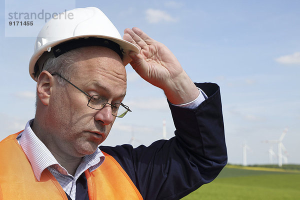Deutschland  Techniker mit Schutzhelm vor Windkraftanlagen