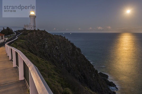 Australien  New South Wales  Byron Bay  Cape Byron Bay Leuchtturm und Vollmond über dem Meer nach Einbruch der Dunkelheit.