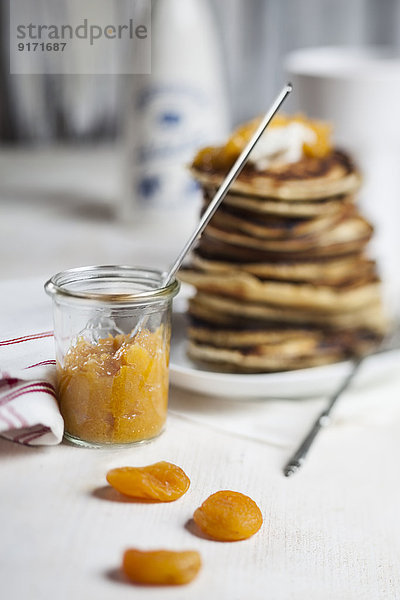 Stapel amerikanischer Pfannkuchen  Glas Aprikosensoße und getrocknete Aprikosen auf dem Tisch