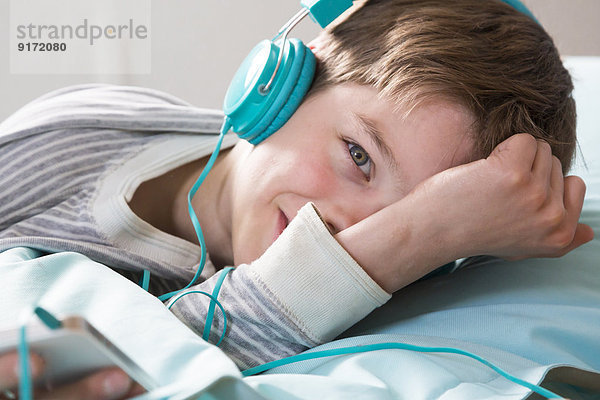 Porträt eines lächelnden Jungen mit Kopfhörer auf Sitzsack liegend