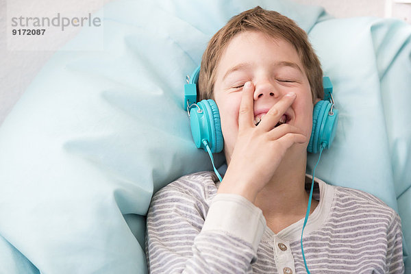 Porträt eines lachenden Jungen  der Musik hört  mit Kopfhörern auf dem Sitzsack.