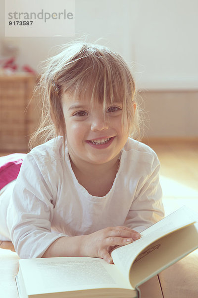 Porträt des lächelnden Mädchens mit Buch