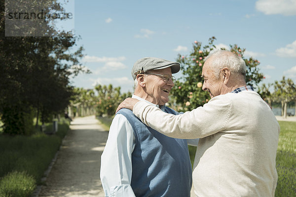 Zwei fröhliche alte Männer stehen sich gegenüber im Park.