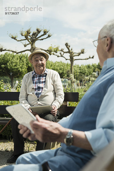 Zwei alte Männer mit Tablet-Computern im Park