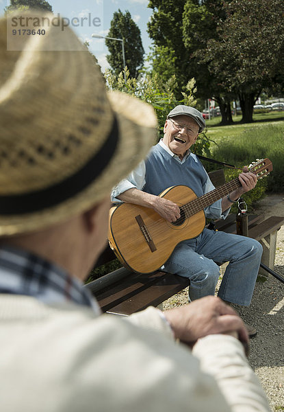 Zwei alte Männer mit Gitarre im Park