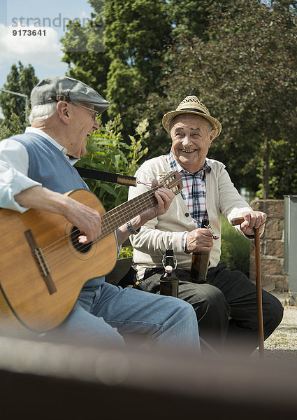 Zwei alte Männer mit Gitarre im Park