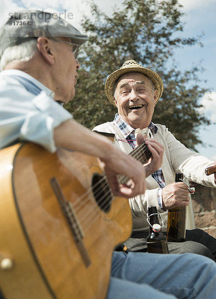 Zwei alte Männer mit Gitarre im Park