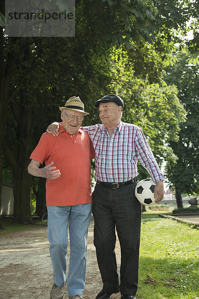 Zwei alte Freunde beim Spaziergang im Park mit Fußball