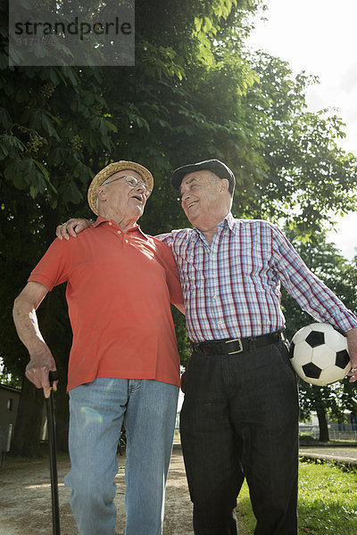 Zwei alte Freunde beim Spaziergang im Park mit Fußball
