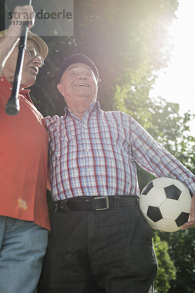 Zwei alte Freunde beim Spaziergang im Park mit Fußball