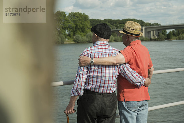 Deutschland  Rheinland-Pfalz  Worms  zwei alte Männer stehen Arm in Arm mit Blick auf den Rhein  Rückansicht