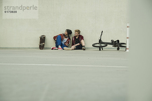 Zwei Jungs mit BMX-Bike und Skateboard auf Parkebene