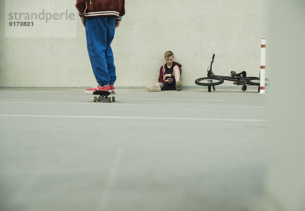 Zwei Jungs mit BMX-Bike und Skateboard auf Parkebene