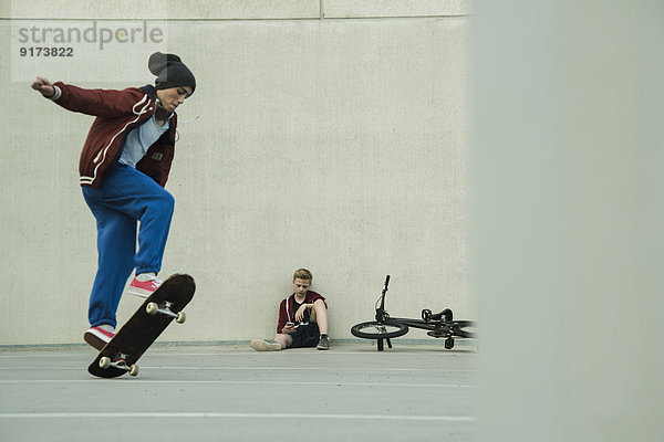 Zwei Jungs mit BMX-Bike und Skateboard auf Parkebene