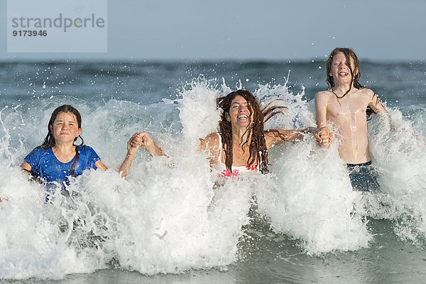 Australien  New South Wales  Pottsville  Familie mit Spaß beim Schwimmen in der Brandung
