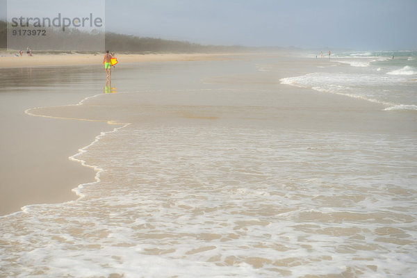 Australia  New South Wales  Pottsville  misty beach with breakwater and a surfer walking in the distance