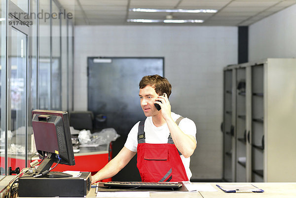Kfz-Mechaniker am Telefon im Servicebereich einer Kfz-Werkstatt