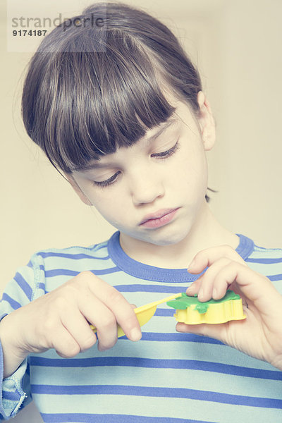 Porträt eines kleinen Mädchens mit Kutter und grüner Modelliermasse