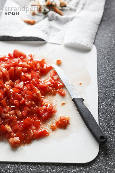 Diced tomatoes and kitchen knife on chopping board