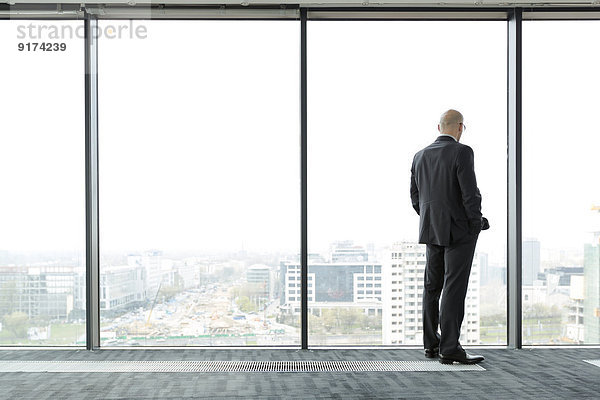Geschäftsmann auf leerer Büroetage mit Blick aus dem Fenster