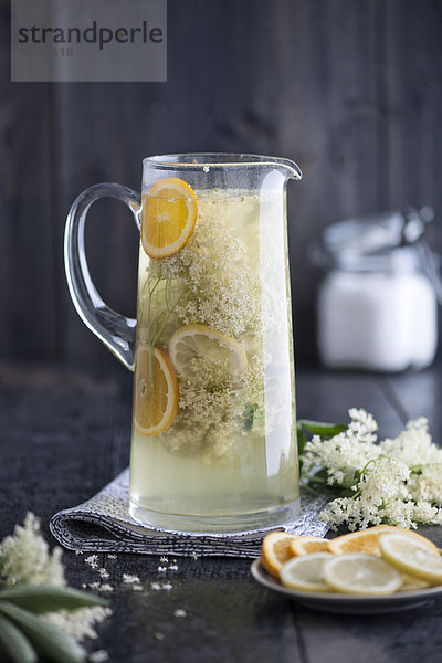 Glas hausgemachter Holunderblütensirup mit Orangen- und Zitronenscheiben
