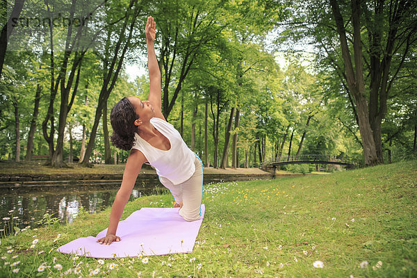 Deutschland  Frau beim Yoga im Park  Triangle Pose