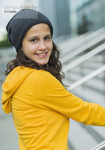 Porträt einer lächelnden jungen Frau im gelben Trainingsanzug und Wollmütze