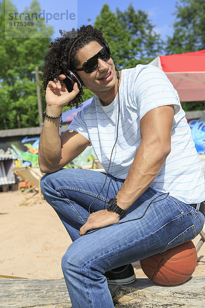 Portrait eines jungen Mannes beim Musikhören am Strand