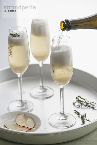 Tablett mit drei Champagnerflöten aus Champagner mit Birnenpurree und Thymian