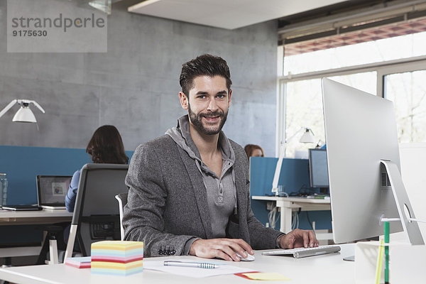 Porträt eines lächelnden Mannes an seinem Arbeitsplatz im Büro