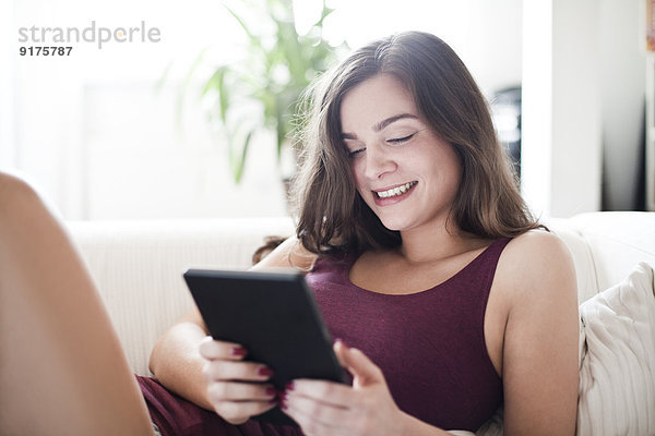 Portrait der lächelnden jungen Frau mit Tablet-Computer zu Hause