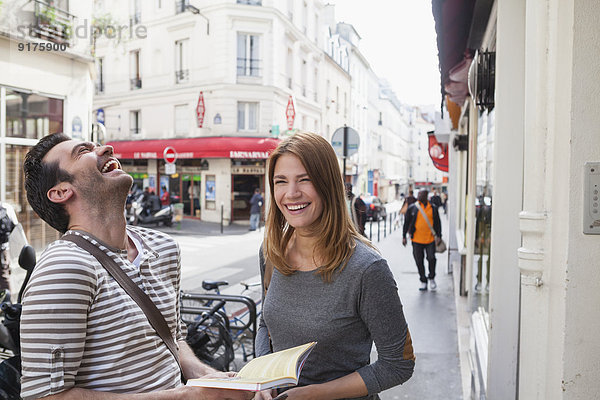 Frankreich  Paris  Portrait eines glücklichen Paares  das die Stadt mit einem Reiseführer erkundet.