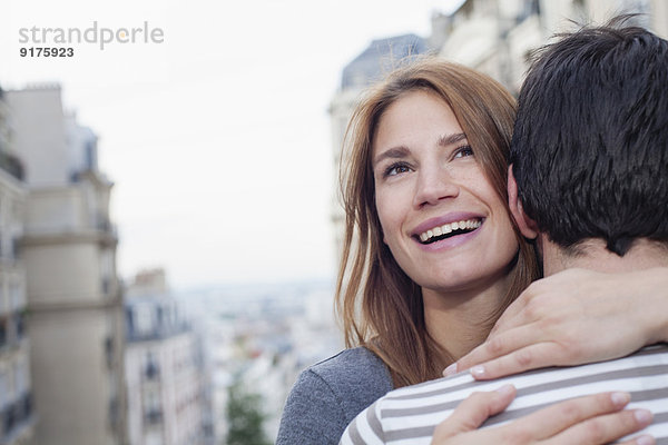 Frankreich  Paris  Porträt einer lächelnden jungen Frau  die ihren Partner umarmt.