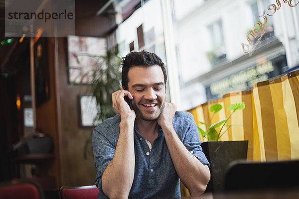 Frankreich  Paris  Porträt eines Mannes  der mit seinem Smartphone in einem Café telefoniert.