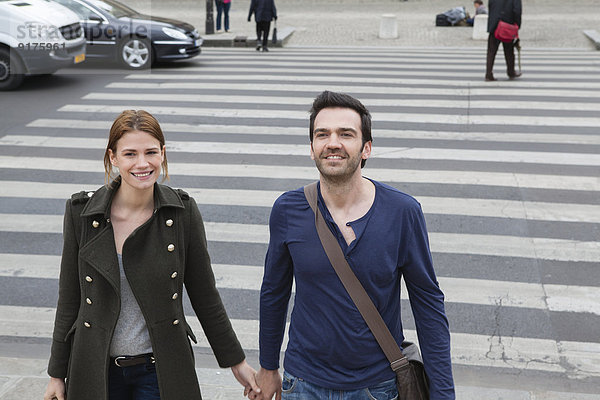 Frankreich  Paris  Paar  das Hand in Hand auf dem Zebrastreifen läuft