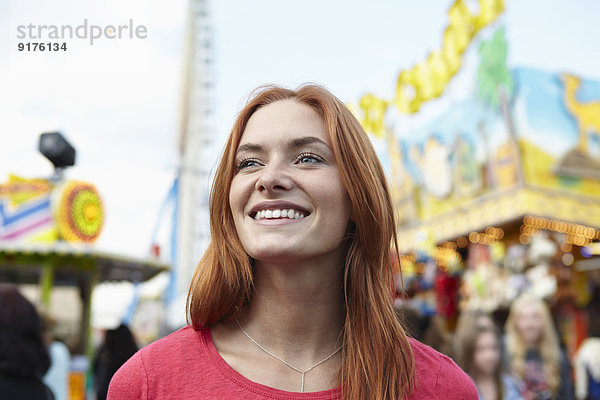 Lächelnde junge Frau auf einem Jahrmarkt