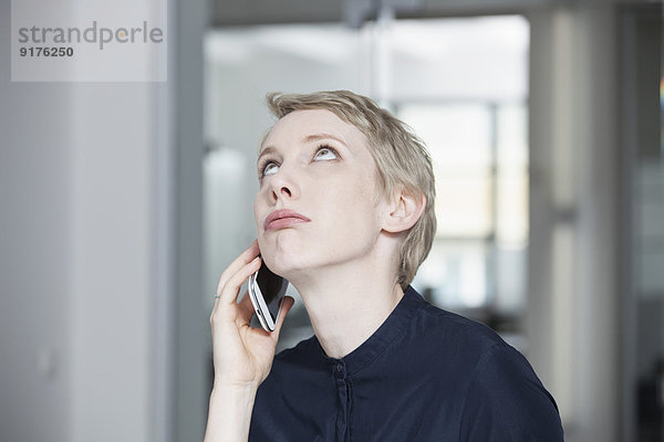 Deutschland  München  Geschäftsfrau im Büro  mit Smartphone