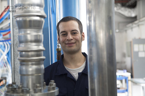 Porträt eines lächelnden Technikers in einer Fabrikhalle